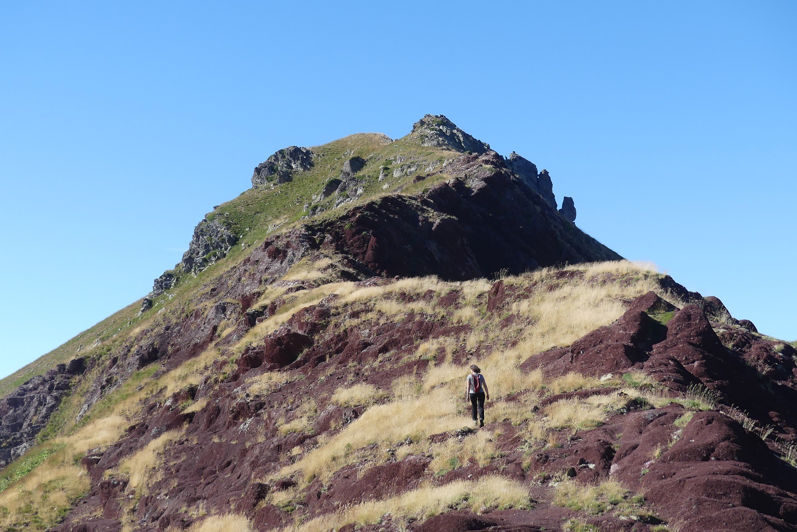 Photo de Christelle sur la crête vers la Punta Espelunciecha, marchant sur une herbe sèche et entourée de roche rouge