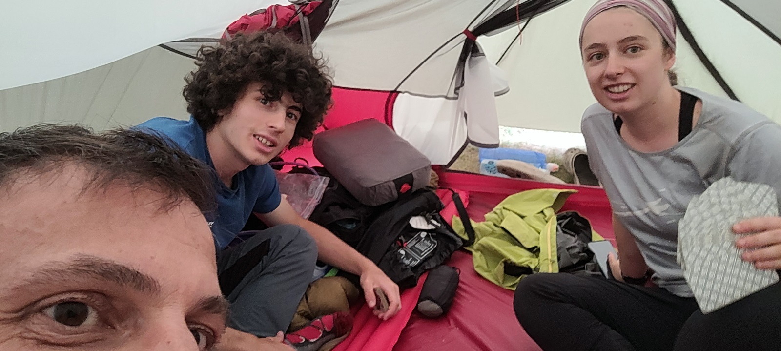Selfie de Seb, Faustin et Charline (qui tient une main de cartes de tarot) sous la tente.