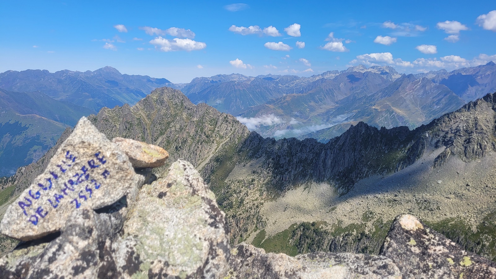 Photo d'une pierre avec écrit "Aiguille de Lahazère" devant le paysage